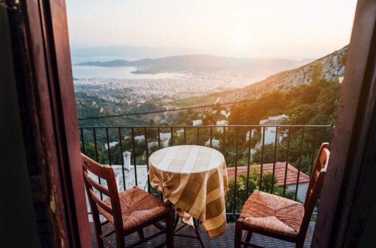 hotel room view from the balcony: two wooden chairs and a table on the background of a beautiful cityscape