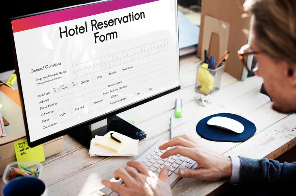 A man filling out a hotel reservation form on a computer screen