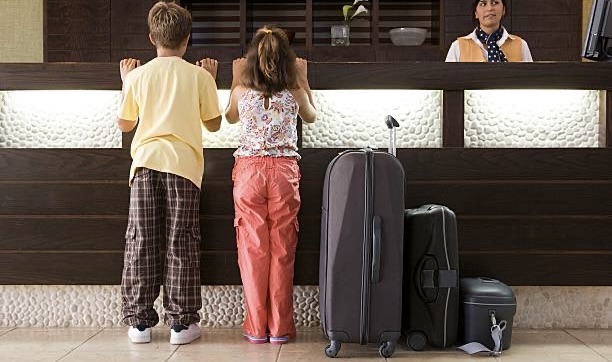 A boy and a girl are standing near the reception desk at a hotel