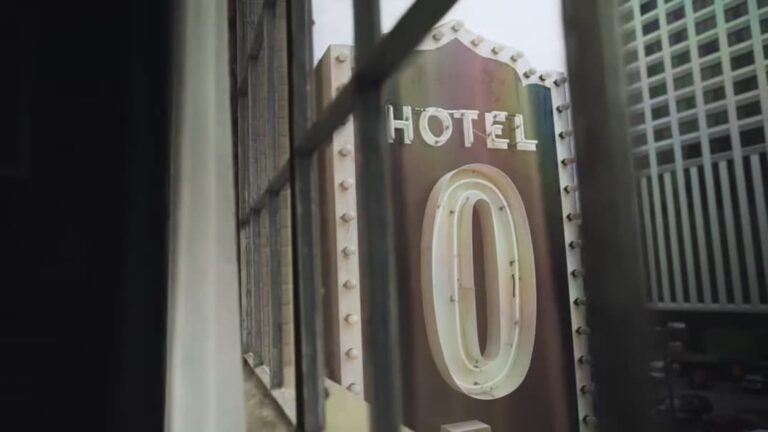 Close-up of a rusty hotel sign with the number "0" viewed through a barred window