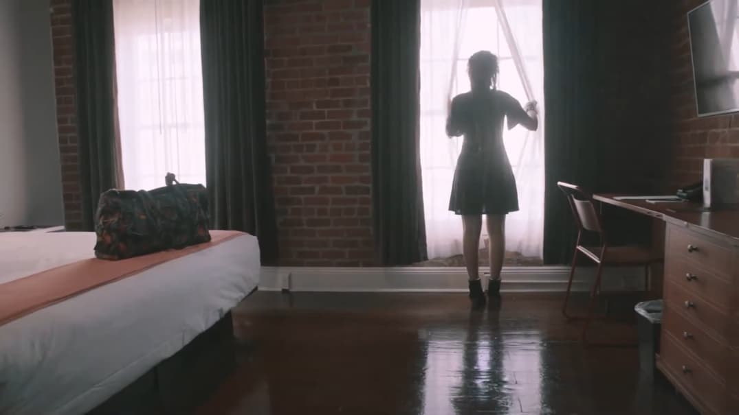 A silhouette of a person standing by a window in a room with exposed brick walls