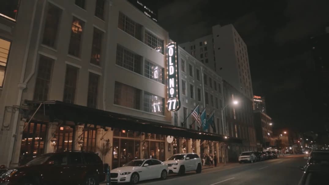 Night view of a hotel's exterior with "OLD NO 77" neon sign lit up on the street side