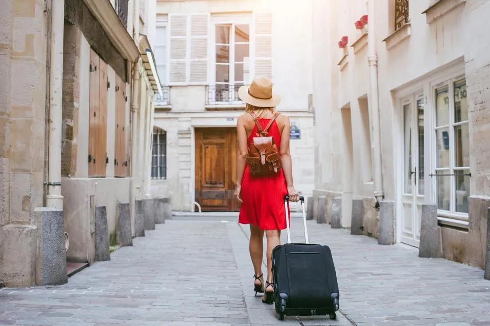 A girl with a suitcase walks towards the hotel