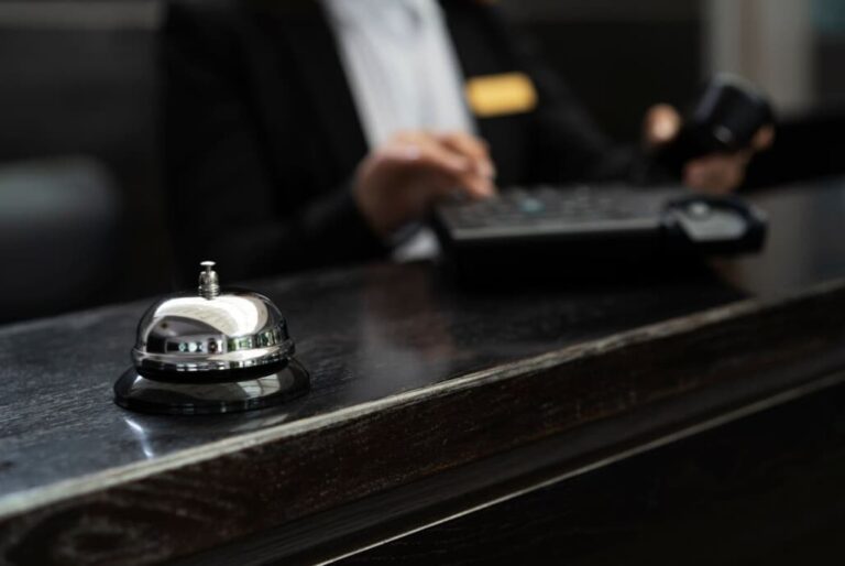 Close-up of a service bell on a hotel's front desk with an employee in the background